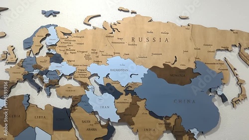 A wide shot of a 3D wooden world map wall decoration, showcasing Eurasia, Russia, China, and parts of Africa in multi-toned wood grains.