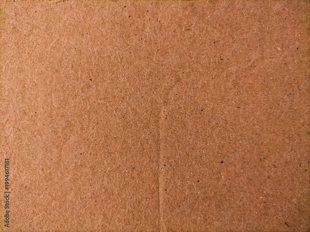 Fototapeta premium Brown cardboard surface with textural detail showing its fibrous material.