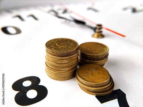 Indonesian rupiah coins are neatly stacked on the face of a large clock.