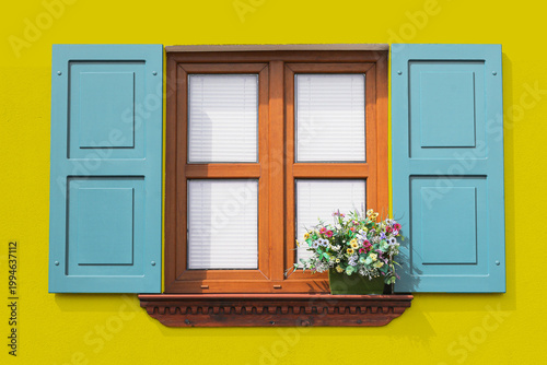 Photos Colorful house window with blue shutters on yellow wall