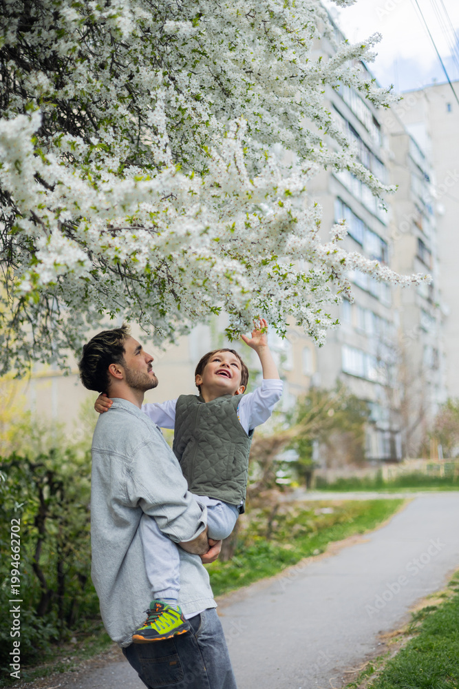 Obraz premium A father and son are enjoying spring and admiring the blooming trees. Springtime. 