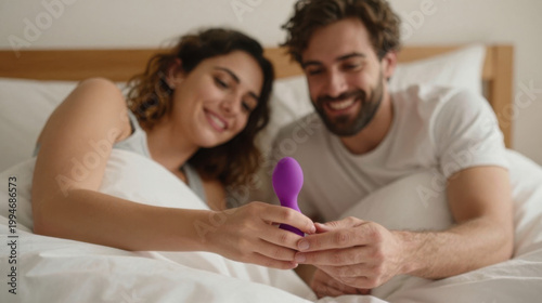 Couple in bed holding purple vibrator