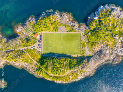 Aerial top down view of the famous Henningsvaer football stadium in Lofoten islands, Norway. Iconic soccer pitch on a rocky island surrounded by the sea. Scandinavian sports landmark from a drone.