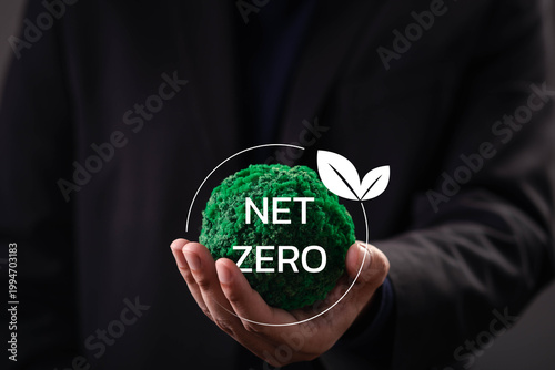 Close-up of a hand holding a green sphere with net zero symbol, representing carbon neutrality, climate action, sustainable business strategy, environmental responsibility, global sustainability goals