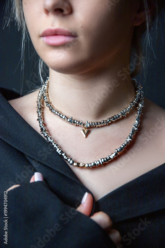 Woman showcasing metallic choker set with heart pendant, refined hand gesture, black fashion