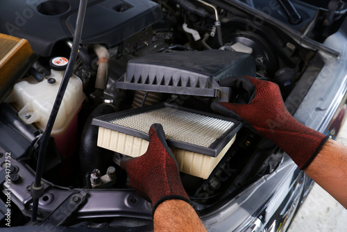 Replacing Car Engine Air Filter, A mechanic wearing gloves replaces a dirty car engine air filter with a clean one to ensure optimal engine performance and efficiency.