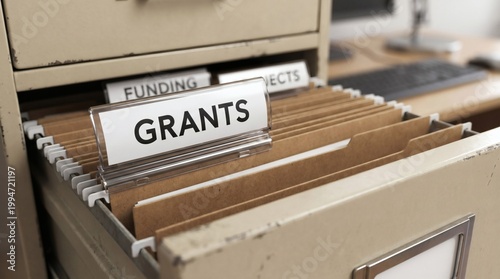 Close up of a folder labeled GRANTS in a metal filing cabinet drawer with funding files.