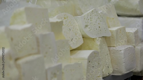 A close-up view of various types of cheese blocks displayed on a market counter, showcasing their textures and natural appearance.