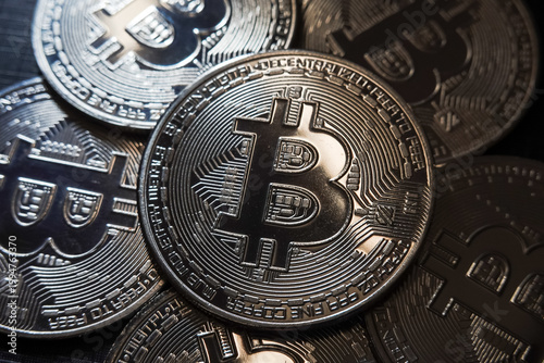 Close-up of Bitcoin cryptocurrency coin surrounded by other digital coins. Concept of blockchain technology, crypto trading, digital assets, and financial investment