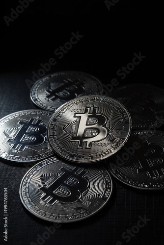 Close-up of Bitcoin cryptocurrency coin surrounded by other digital coins. Concept of blockchain technology, crypto trading, digital assets, and financial investment