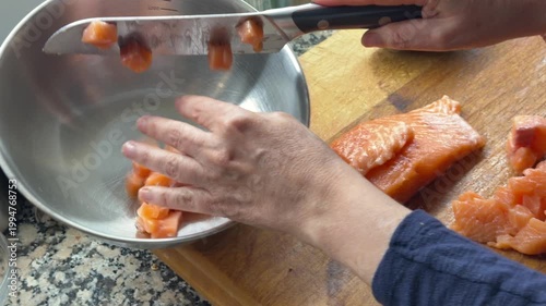 Adding raw salmon cubes into bowl for poke preparation