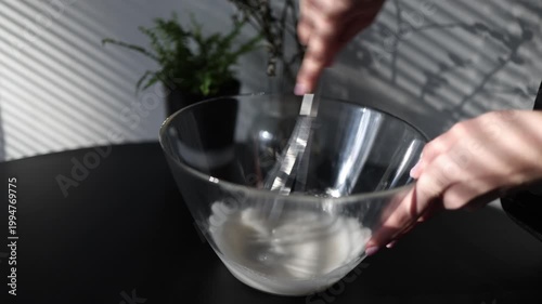 Female hands whisk egg whites in transparent bowl soft airy texture cooking process baking preparation close up kitchen scene
