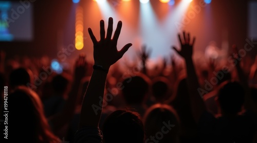 Large crowd engaged in worship with hands raised during an uplifting church event in a vibrant atmosphere at a community center in the evening 
