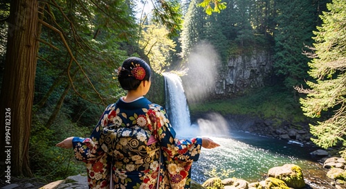 Peaceful woman in a traditional kimono enjoying the majestic view of a cascading waterfall surrounded by lush green forest and bright sunlight