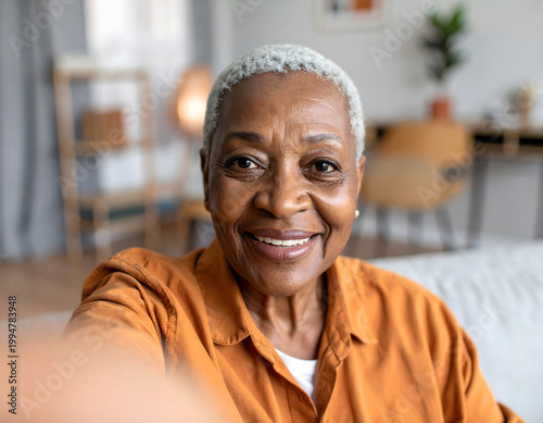 Senior Tech Literacy: Magazine style documentary image of senior woman video calling family with joyful expression showing love and connection at home