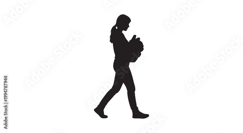 Silhouette of a young woman walking while holding a small puppy