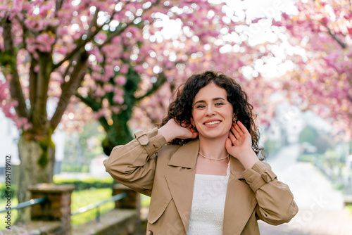 Closeup Portrait of young woman near blooming pink sakura. Spring. Unity with nature.