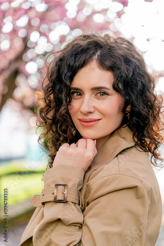 Closeup Portrait of young woman near blooming pink sakura. Spring. Unity with nature.
