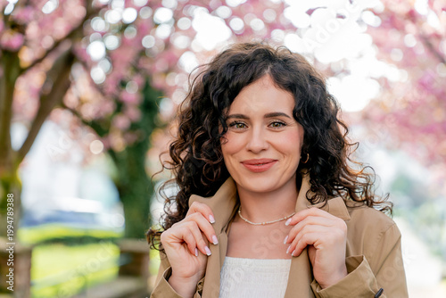 Closeup Portrait of young woman near blooming pink sakura. Spring. Unity with nature.