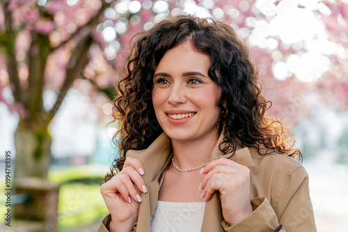 Closeup Portrait of young woman near blooming pink sakura. Spring. Unity with nature.