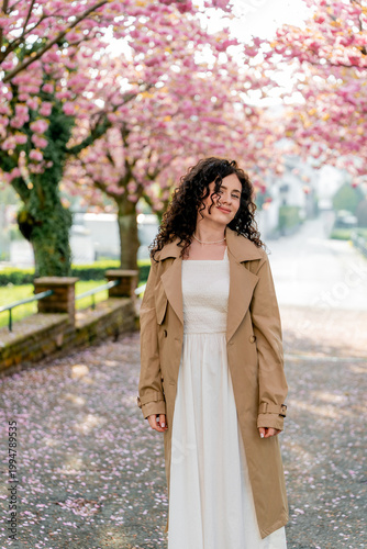 Young woman resting near blooming pink sakura. Spring. Unity with nature.