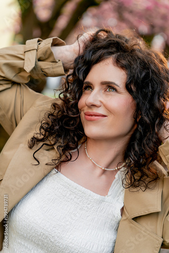 Closeup Portrait of young woman near blooming pink sakura. Spring. Unity with nature.