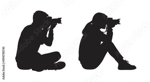 Two photographers are captured in silhouette focusing with their cameras