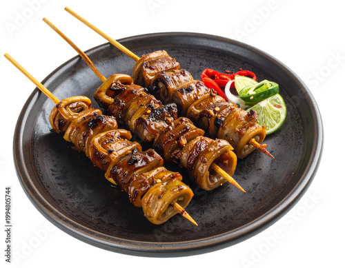 Savory grilled meat skewers served on a dark plate with lime