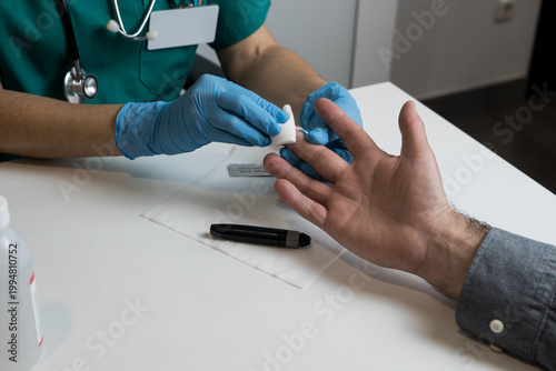 Obraz na płótnie A medical professional cleaning a patient's fingertip with an alcohol swab to ensure a sterile procedure for glucose level testing