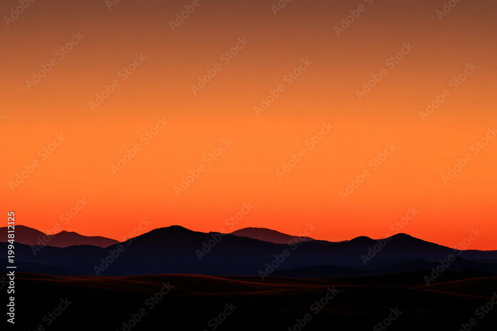 Obraz premium dramatic mountain silhouette against a vibrant orange sunset sky