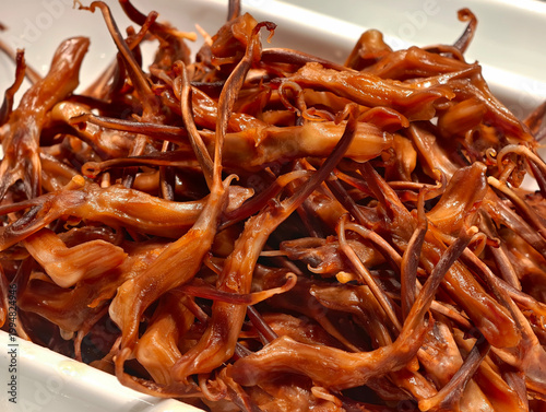 Close-up of braised duck tongues in a white container