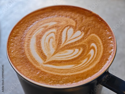 Top view of a latte coffee with intricate heart and leaf pattern latte art on the surface