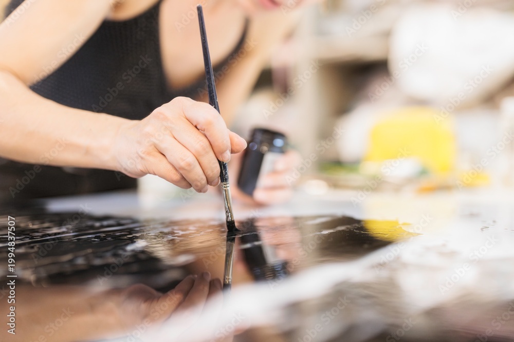 Obraz premium A skilled artisan carefully applies gold foil to a glass surface, creating stunning artwork that enhances luxury furniture and decorations with a rich, exquisite finish