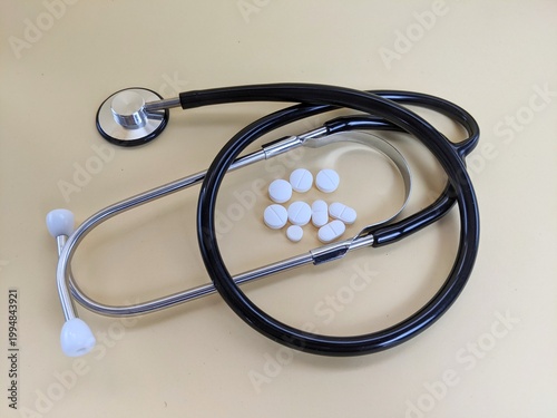 stethoscope on white background. Stethoscope with white tablets symbolizing healthcare, medical diagnosis and treatment on a neutral background.
