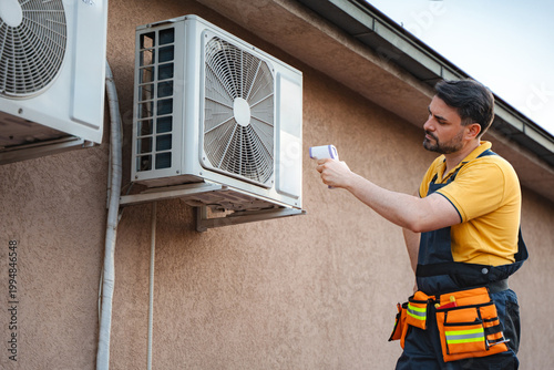 Slika na platnu Technician using infrared thermal gun to check air conditioning unit