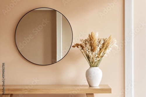 Mirror and Flower Vase on Wooden Table Against Beige Wall