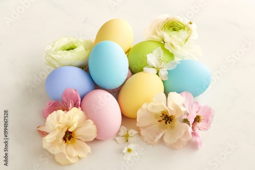 Colorful Eggs and Flowers Arranged on a Light Background for a Spring Celebra...