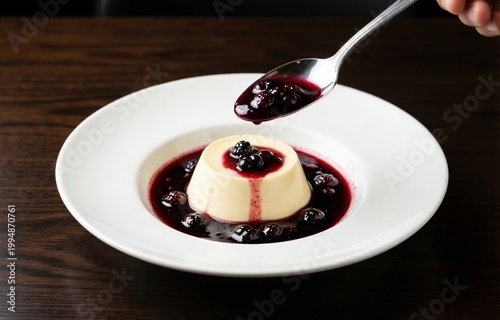 Close-up of Panna Cotta topped with blueberries on white plate. Concept of creamy dessert experience featuring cream pudding with vanilla berry sauce. 