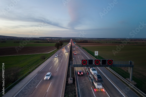Aerial view of highway with moving vehicles and speed limit signs during dawn