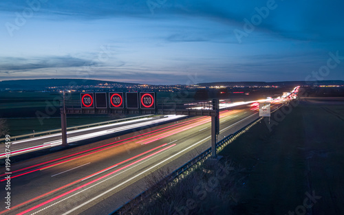 Schilderij op canvas Highway traffic at night with speed limit signs and light trails