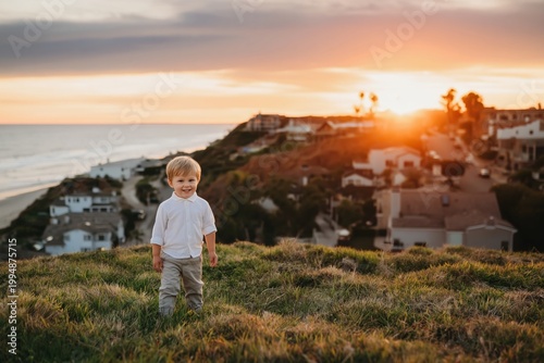 Child Stands on Grass at Sunset Near Houses Overlooking Beach in California