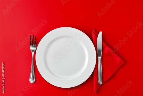 Table Setting With Cutlery and a Blank Plate on a Red Background