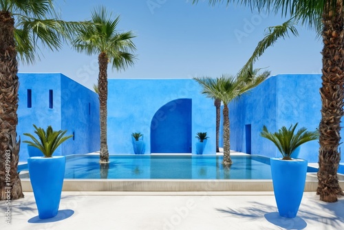 Bright Blue Walls and Palm Trees Surround a Swimming Pool in a Courtyard Duri...