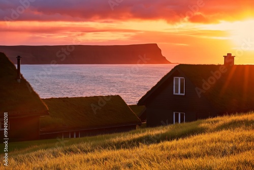 Sunset Over Grassy Hills and Houses Near the Coast With Distant Cliffs in the...