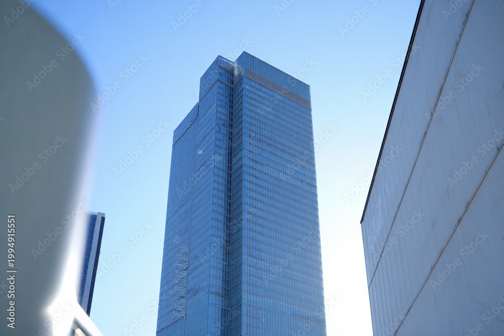 Obraz premium Tall glass skyscraper against bright blue sky