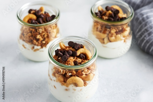 Three Jars Filled With Yogurt, Granola, Nuts, and Chocolate Chips on a Simple...