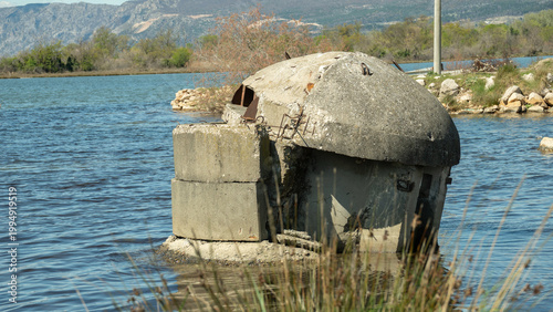 Obraz na plátně A crumbling communist-era concrete bunker sits partially submerged in the blue waters of a lagoon in Ishull Lezhë, Albania, reflecting a turbulent history