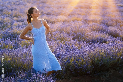 Young Woman Stands in Lavender Field During Golden Hour With Sunlight Shining