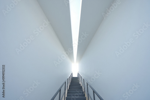 Stairway leading to bright light in minimalist architectural space