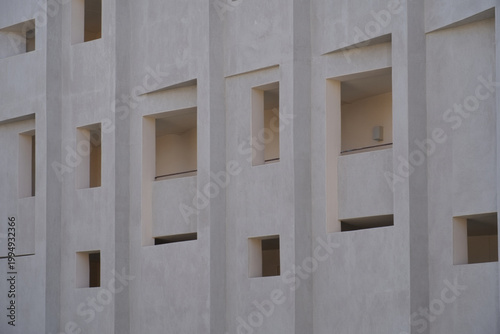 Concrete building facade with recessed square windows and balconies